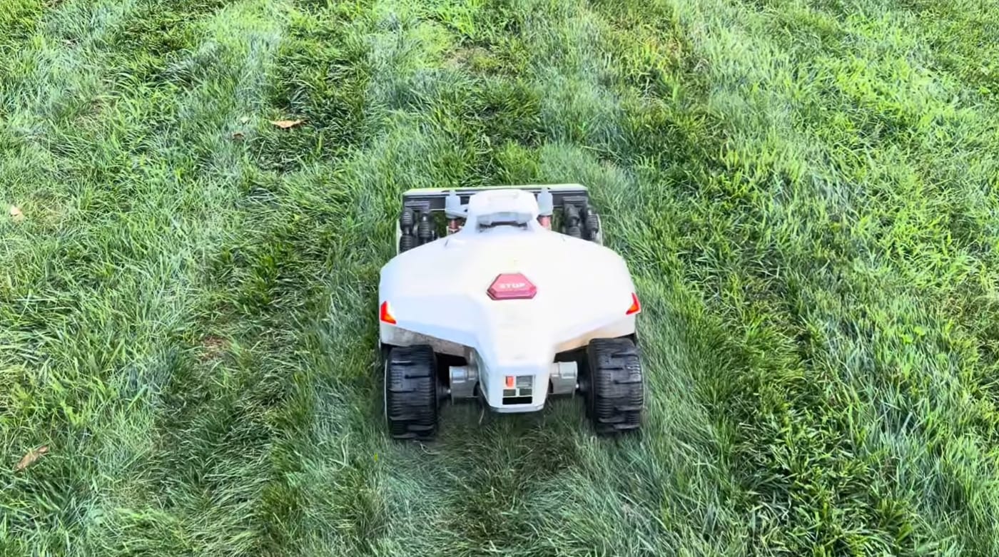 A Mammotion LUBA 2 robot mower cutting clean stripes into a green backyard lawn