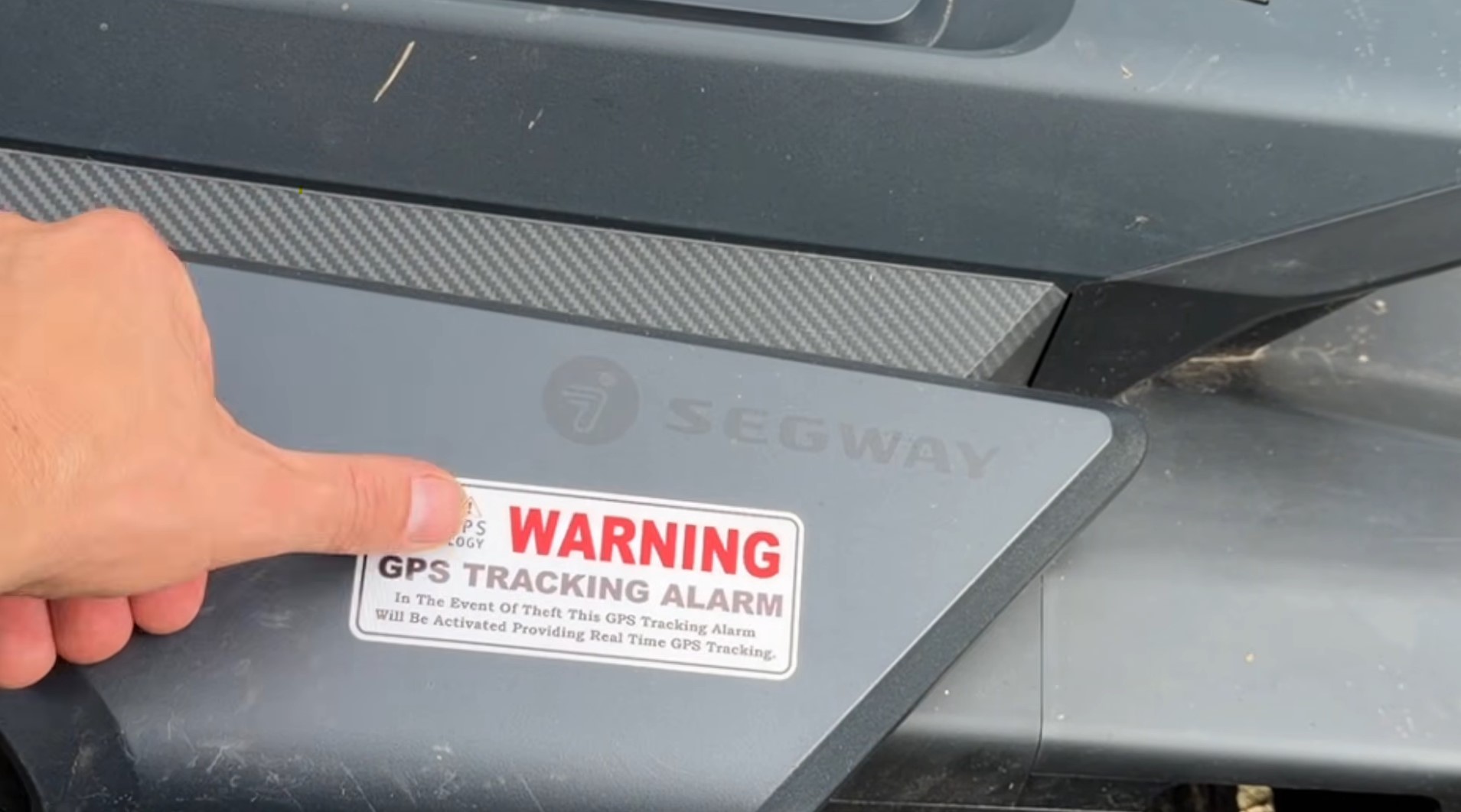 A red and white GPS Tracking Alarm warning sticker on the side of a Segway Navimow mower