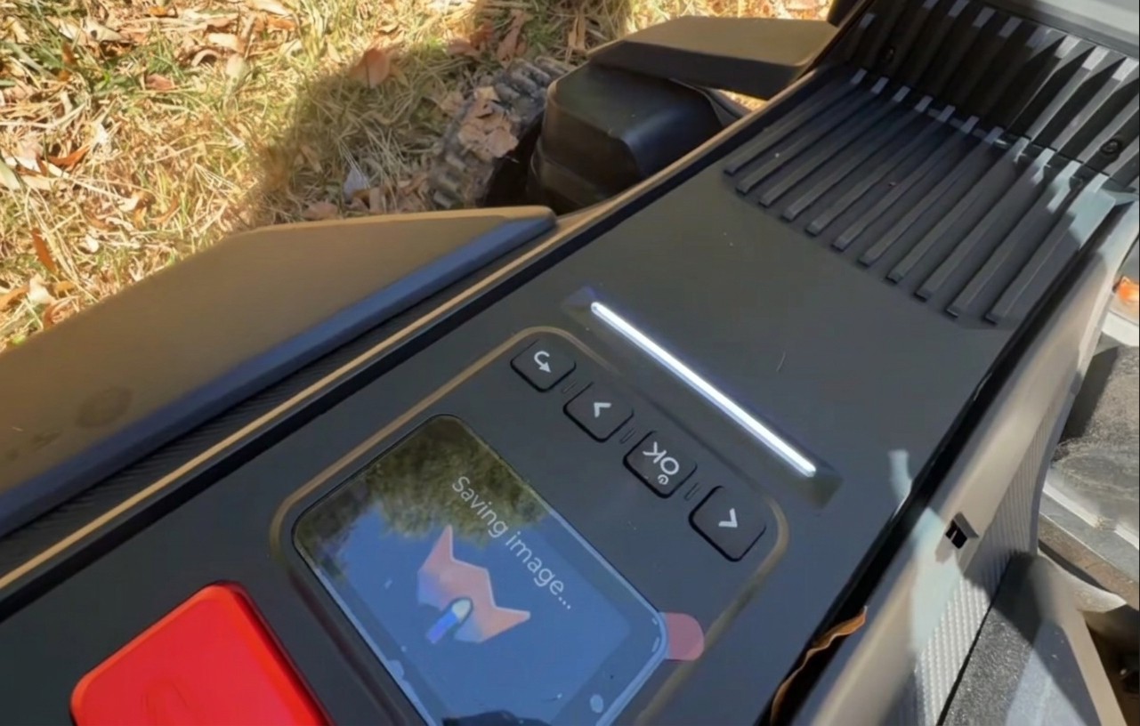 The control panel of a Navimow X430, its light bar glowing white while the display reads Saving image, after the cameras spotted an obstacle