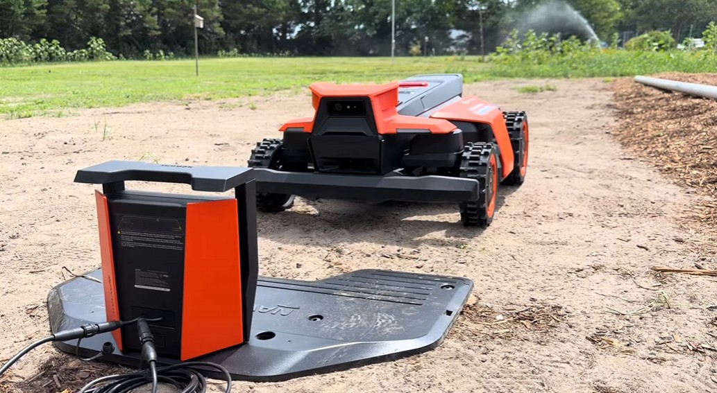 A Segway Navimow Terranox beside its commercial charging station in a field