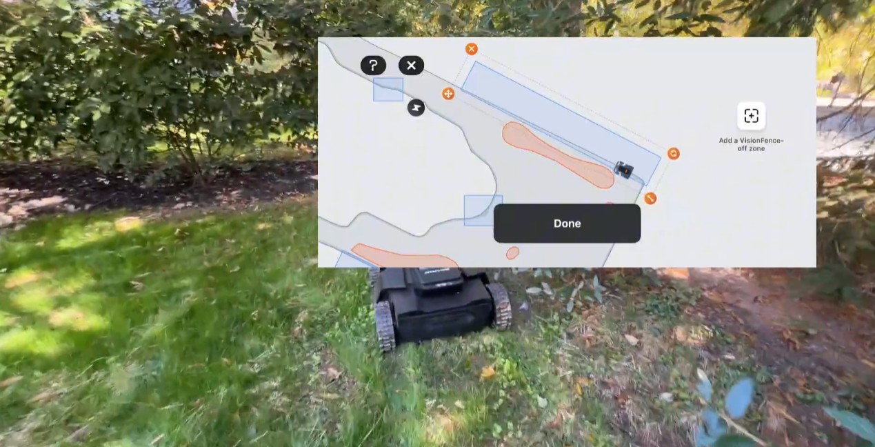 The Navimow app's map editor with an Add a VisionFence-off zone button, shown over a Navimow X430 parked under a low shrub at a Phoenixville, PA lawn