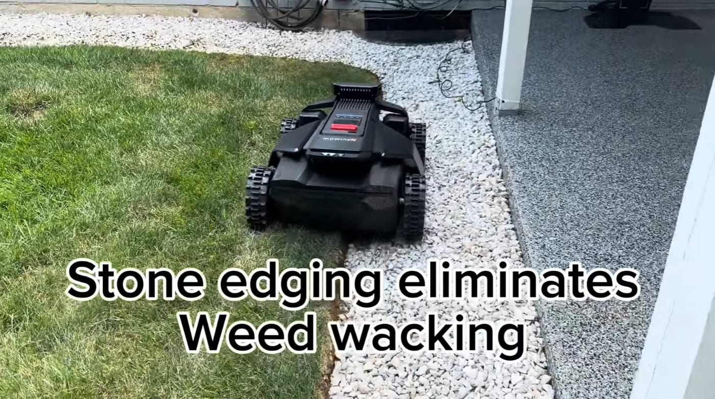 A robot mower cutting right up to a clean white-stone border with no strip of uncut grass left behind