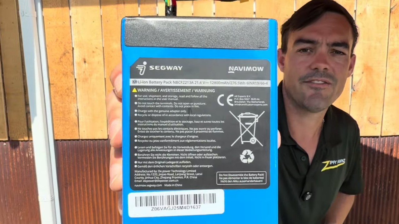 A Segway Navimow 12.8Ah, 276.5Wh lithium-ion robot mower battery pack held up to the camera
