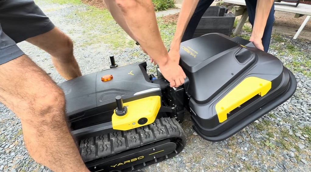 Hands attaching a snap-on module to the Yarbo M Series tracked Core