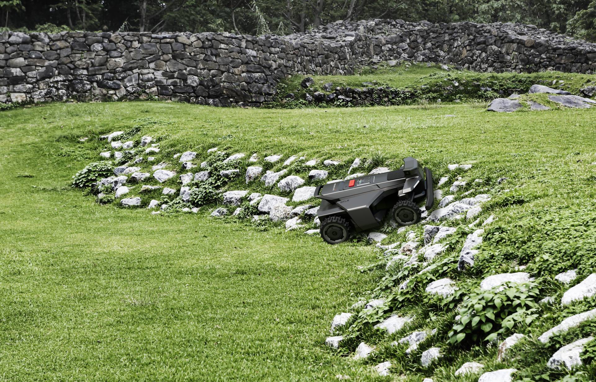 A robotic mower crossing a flush turf-to-gravel-path transition in a designed landscape