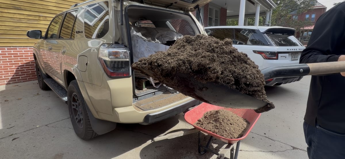 A shovel of compost into a wheelbarrow