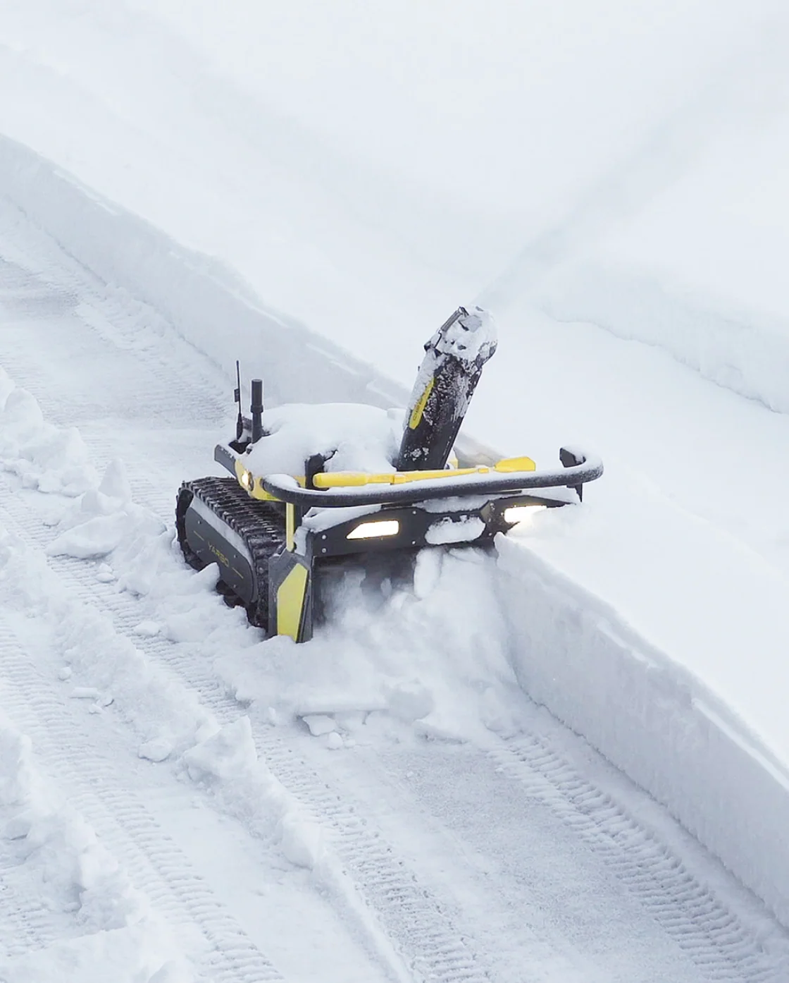The Yarbo Snow Blower working a deep cut, buried to the handle and still moving — tracked, self-driving, unbothered