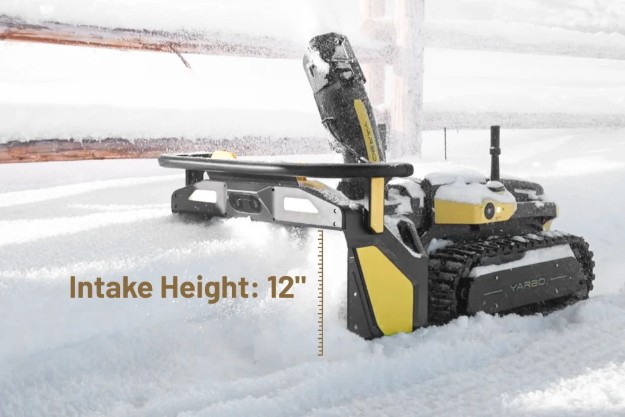 The Yarbo Snow Blower in deep snow by a fence rail — the intake swallows up to 12 inches per pass